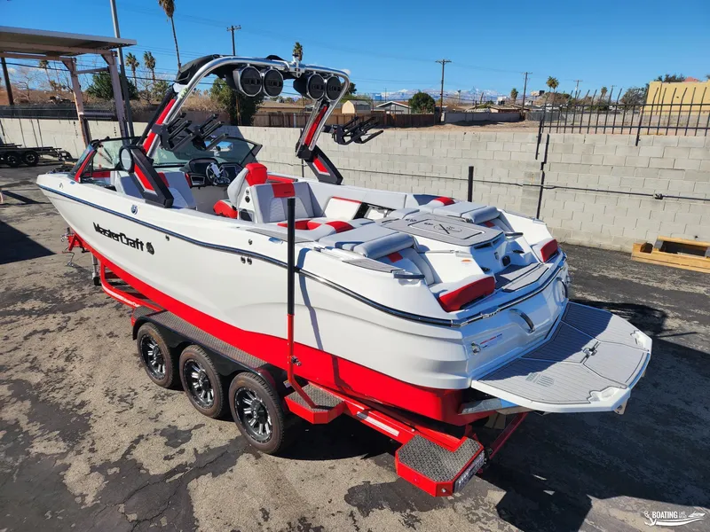 Slide: The Image of 2023 MasterCraft X26 boat on trailer, white and red design, parked outdoors. - 3