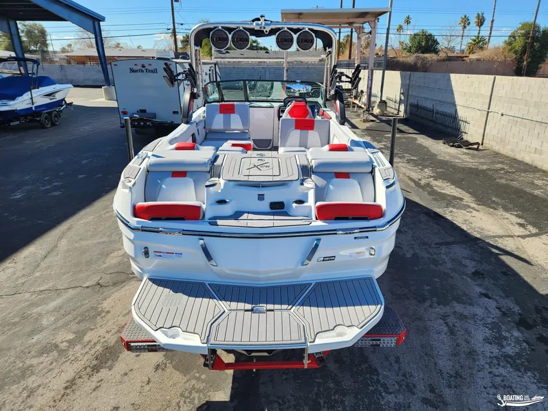 Slide: The Image of 2023 MasterCraft X26 boat with red and white interior, parked outdoors. - 4