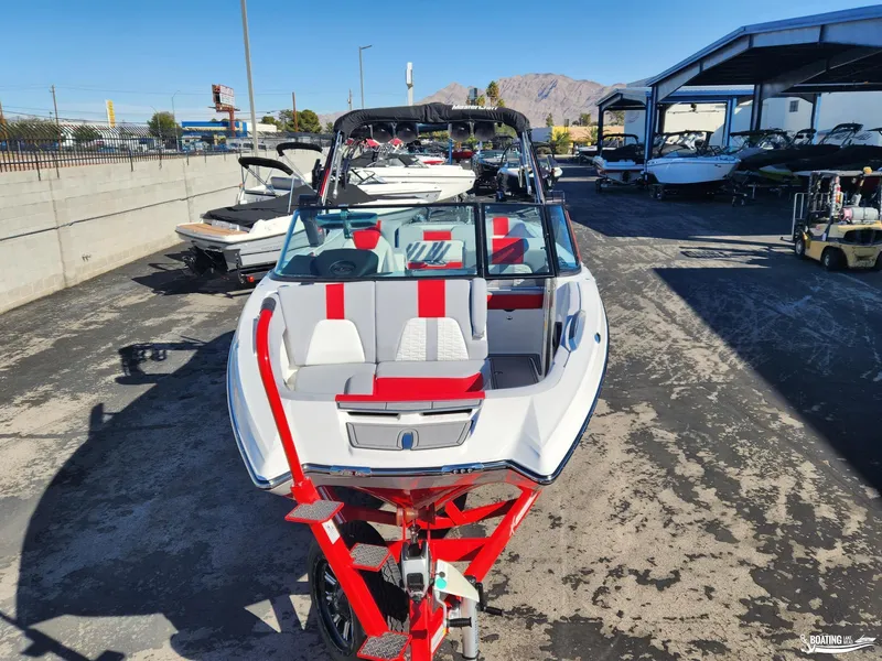 Slide: The Image of 2023 MasterCraft X26 boat with red accents on a trailer in a marina. - 5