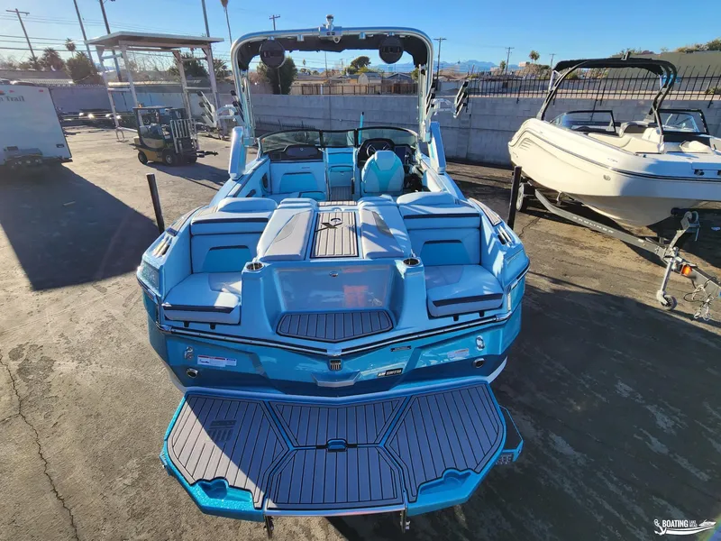 Slide: The Image of 2023 MasterCraft XStar S boat, vibrant blue, parked outdoors, showcasing spacious seating and sleek design. - 11