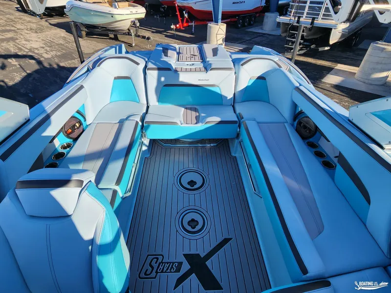 Slide: The Image of 2023 MasterCraft XStar S interior with blue and gray seating, cup holders, and speakers. - 16
