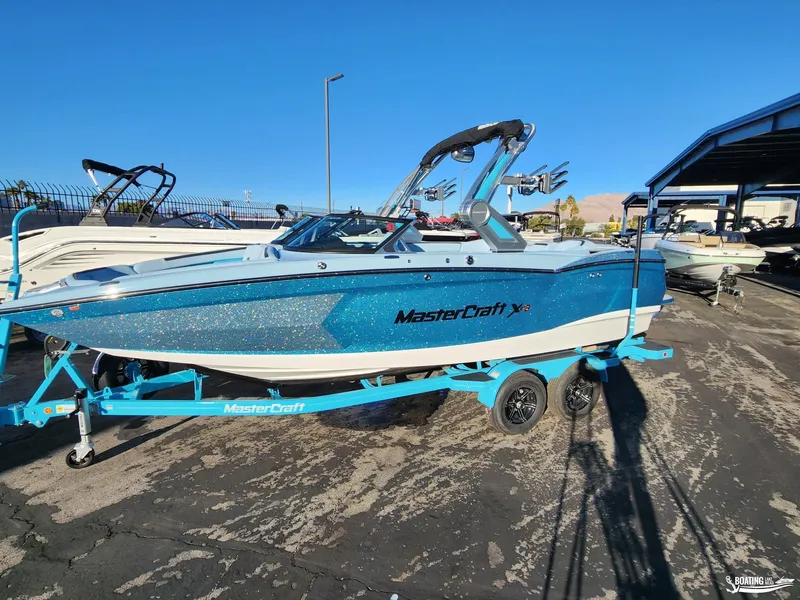 Slide: The Image of 2023 MasterCraft XStar S boat on trailer, sparkling blue finish, parked outdoors. - 18