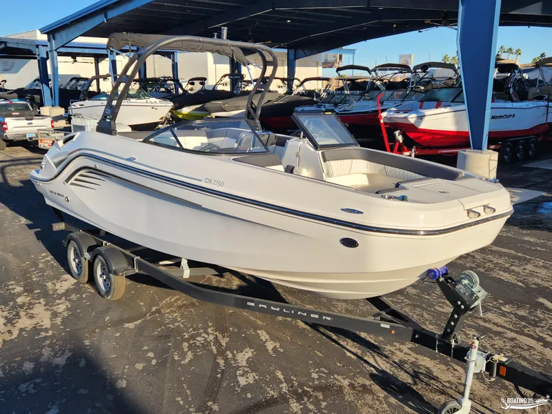 Slide: The Image of 2023 Bayliner DX2250 boat on trailer in marina setting. - 2