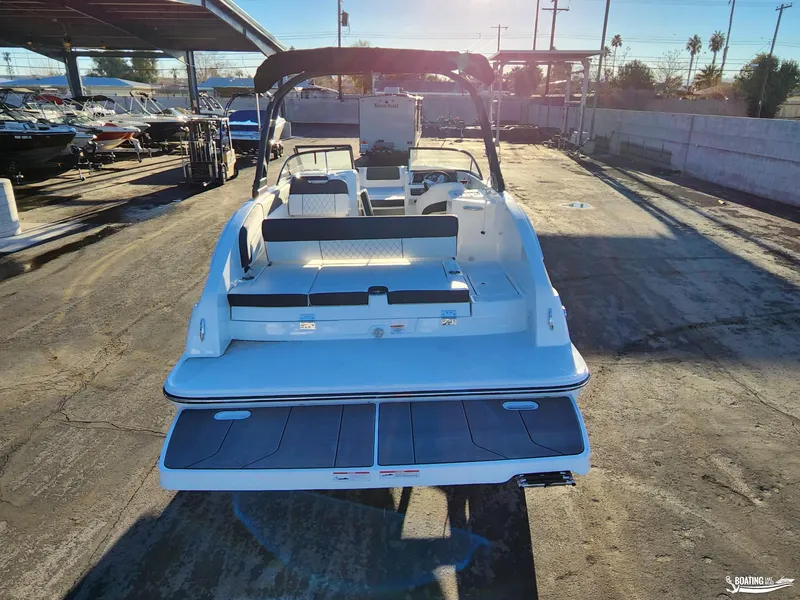 Slide: The Image of 2023 Bayliner DX2250 boat with spacious deck and seating, parked outdoors. - 4