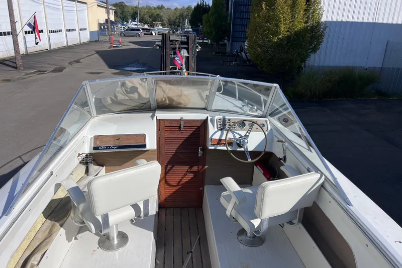 Slide: The Image of 1972 Chris-Craft Launch 23 boat interior with steering wheel and seating, docked outdoors. - 14