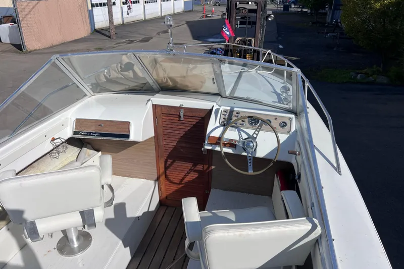 Slide: The Image of 1972 Chris-Craft Launch 23 boat interior with steering wheel and seating, docked outdoors. - 16