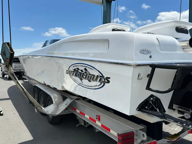 The Image of 2003 Outerlimits 47 GTX powerboat on trailer under clear blue sky. - 14