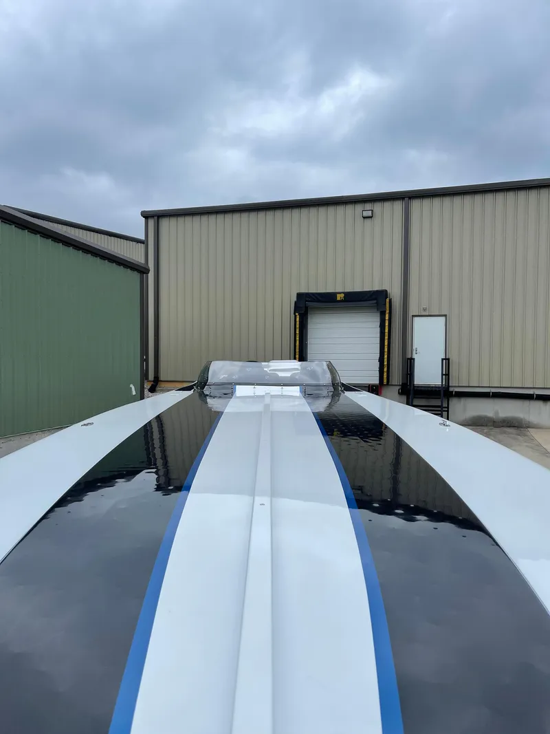 Slide: The Image of 2003 Outerlimits 47 GTX boat with sleek design, parked near industrial building. - 27