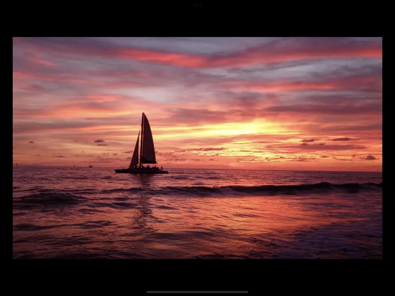 Slide: The Image of Sailing Robertson Custom Catamaran at sunset, 1992 model, on calm ocean waters. - 2