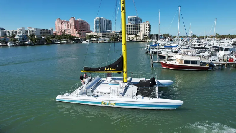 Slide: The Image of Robertson Custom Catamaran Sloop Rig 1992 sailing near marina with cityscape background. - 20