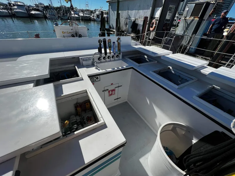 Slide: The Image of 1992 Robertson Custom Catamaran Sloop Rig with open storage compartments and docked at marina. - 38