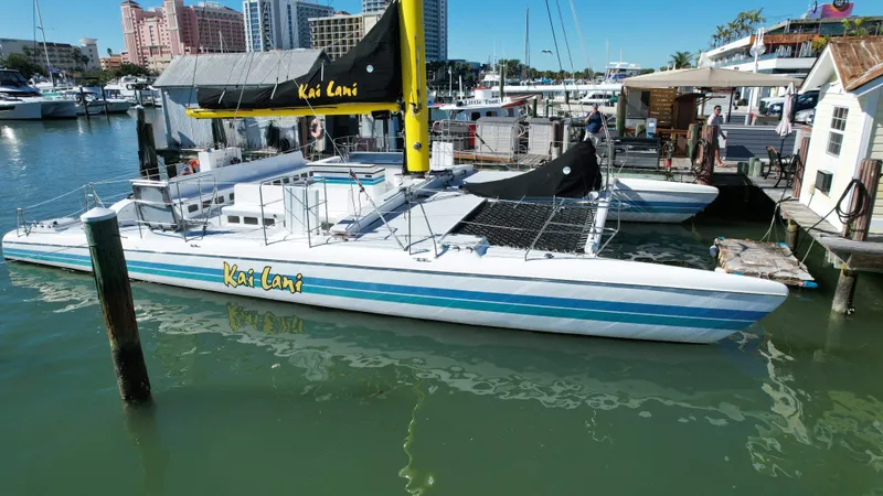 Slide: The Image of Robertson Custom Catamaran Sloop Rig 1992 docked at marina with cityscape background. - 6