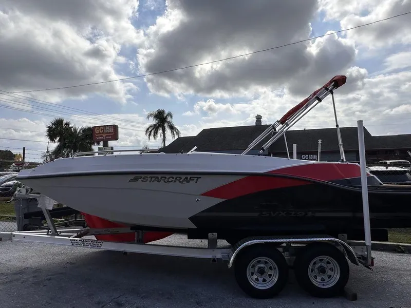 Slide: The Image of 2023 Starcraft SVX OB 191 OB boat on a trailer under a cloudy sky. - 2