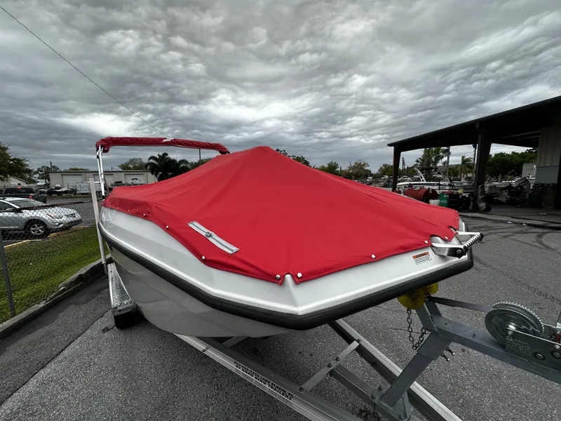 Slide: The Image of 2023 Starcraft SVX OB 191 boat with red cover on trailer, cloudy sky background. - 5
