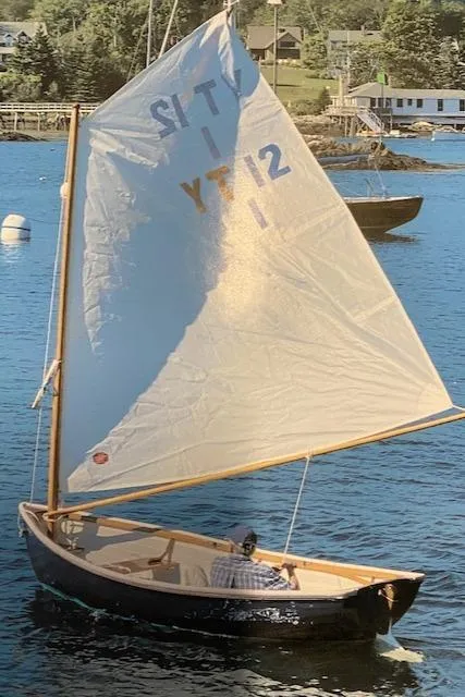 Slide: The Image of 1973 Stanley Herreshoff Yacht Tender sailing on a calm lake with scenic background. - 2