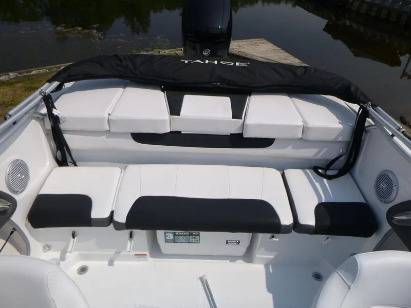 Slide: The Image of 2023 Tahoe 200 S boat interior with white and black seating, docked by a lake. - 9