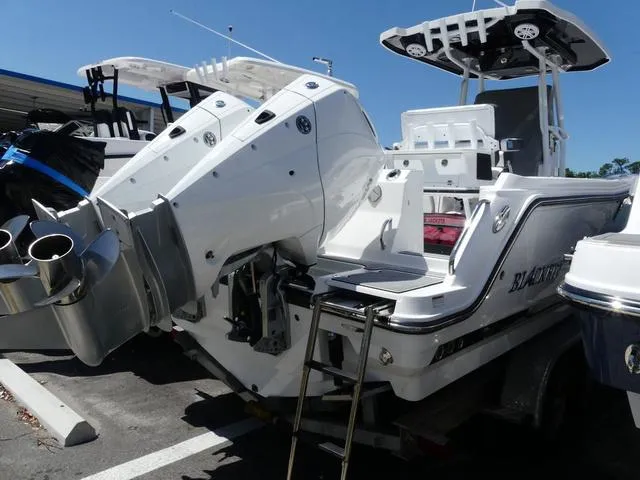 Slide: The Image of 2022 Blackfin 252CC boat with dual outboard engines, parked on a trailer. - 3