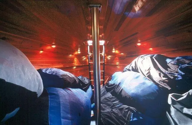 Slide: The Image of Interior of a 1996 Custom 100' Sailing Yacht with wooden paneling and storage bags. - 34