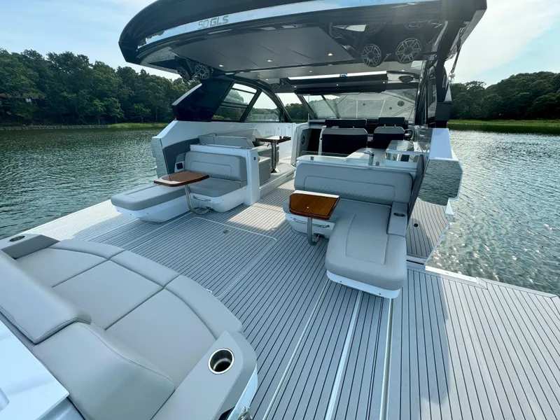 Slide: The Image of 2025 Cruisers Yachts 50 GLS Outboard luxury boat interior with seating and tables on a serene lake. - 43
