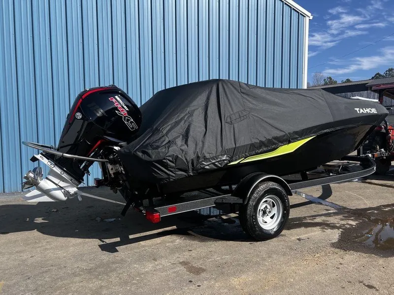 Slide: The Image of 2023 Tahoe T18 boat covered on trailer, parked by blue building. - 3