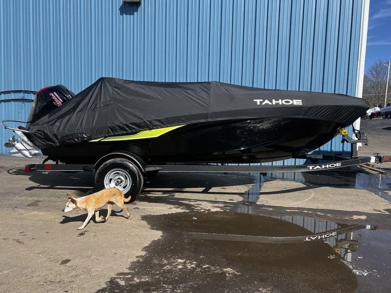 Slide: The Image of 2023 Tahoe T18 boat covered, parked on trailer, with a dog walking nearby. - 6