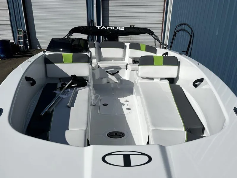 Slide: The Image of 2023 Tahoe T18 boat with sleek white and green interior, docked near blue building. - 9