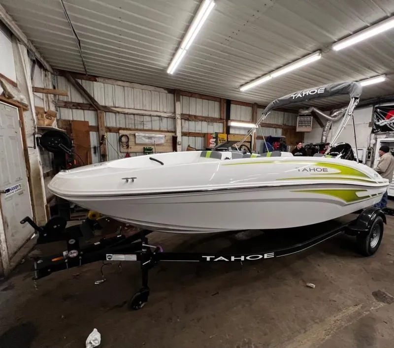 The Image of 2023 Tahoe T16 boat in a garage, white with green accents, on a trailer. - 1