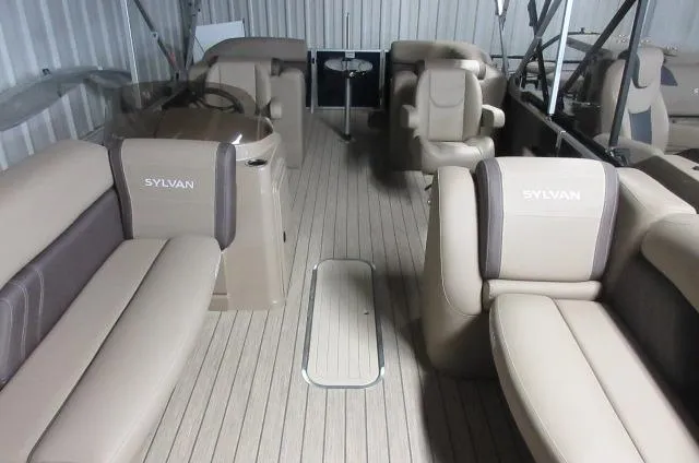Slide: The Image of 2023 Sylvan Mirage 8524 LZ pontoon boat interior with beige seating and wood flooring. - 1