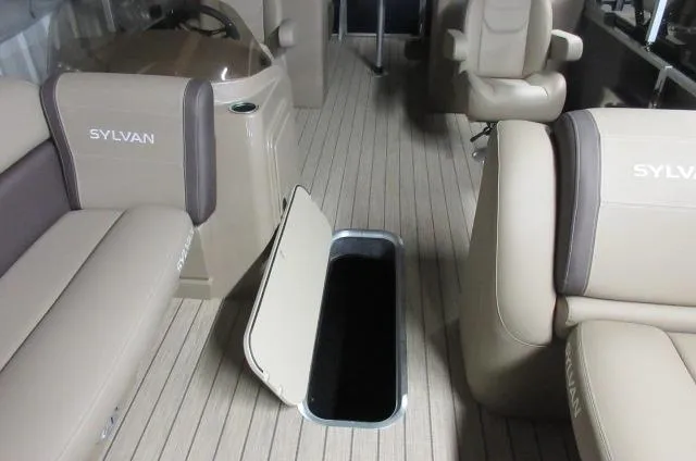 Slide: The Image of 2023 Sylvan Mirage 8524 LZ interior with open storage compartment and beige seating. - 2