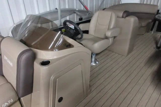 Slide: The Image of 2023 Sylvan Mirage 8524 LZ boat interior with beige seating and steering console. - 3