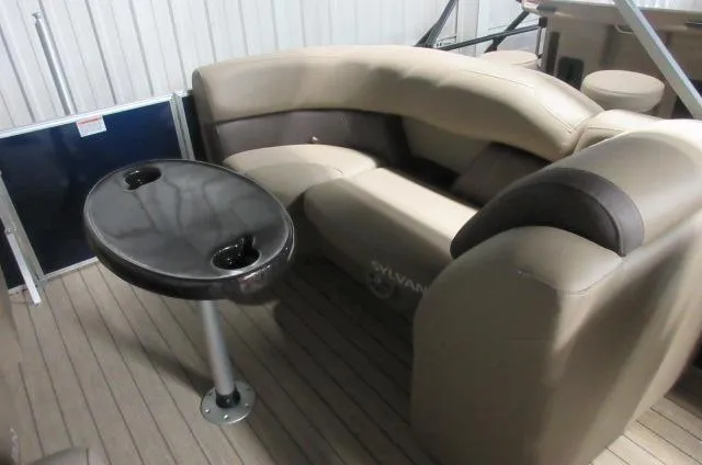 Slide: The Image of 2023 Sylvan Mirage 8524 LZ pontoon boat interior with beige seating and black table. - 8