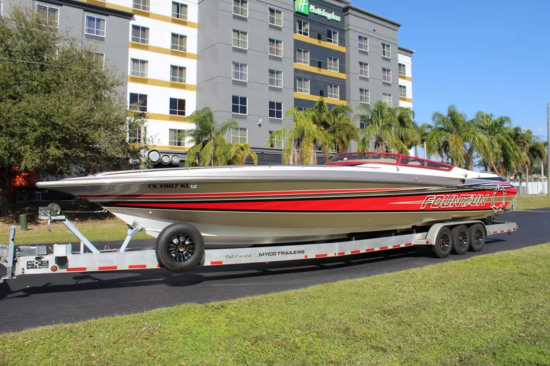 Slide: The Image of A 2007 Fountain 42 Lightning on a trailer in front of a modern building with palm trees. - 1