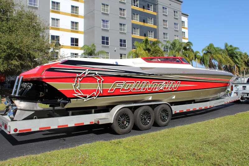 Slide: The Image of A 2007 Fountain 42 Lightning boat on a trailer, featuring bold red and gold design, in front of a building. - 13