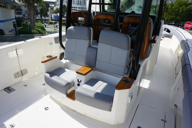 Slide: The Image of 2024 Boston Whaler 360 Outrage boat interior with cushioned seating and wooden accents. - 10