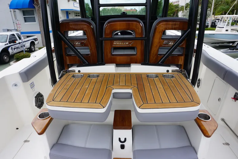 Slide: The Image of 2024 Boston Whaler 360 Outrage boat interior with wooden seating and cup holders. - 40