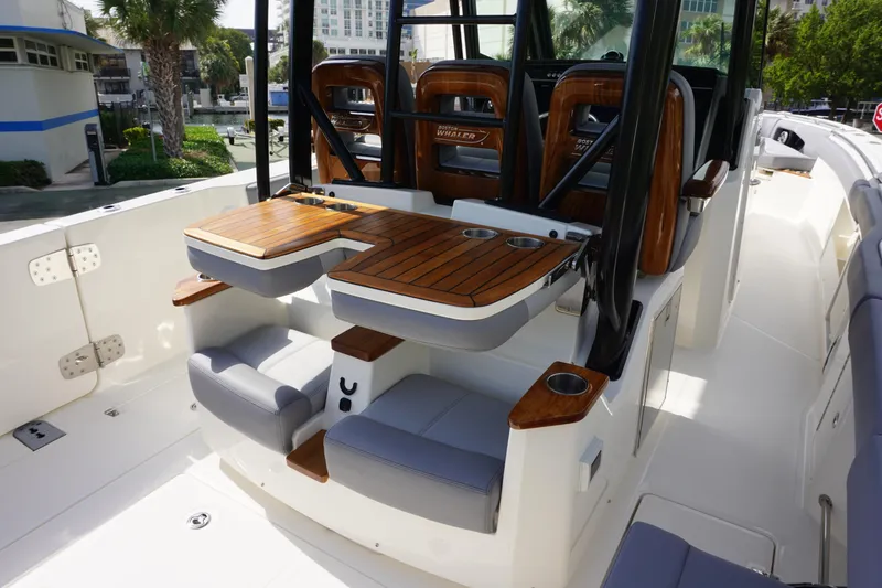 Slide: The Image of 2024 Boston Whaler 360 Outrage boat interior with seating and wooden tables. - 7