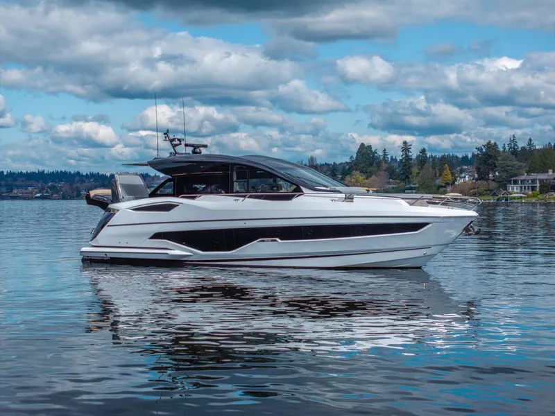 The Image of 2025 Sunseeker Predator 55 yacht cruising on a serene waterway with industrial backdrop. - 0