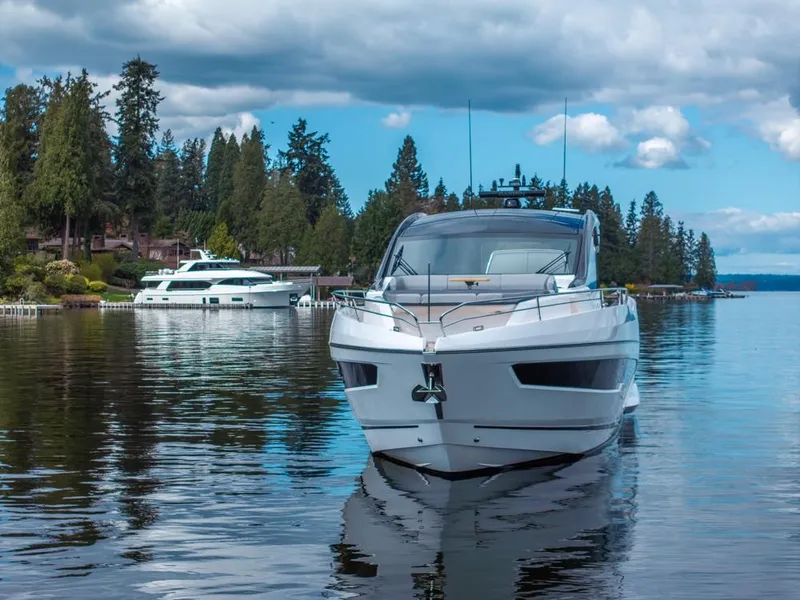 Slide: The Image of 2025 Sunseeker Predator 55 yacht on serene lake with cloudy sky backdrop. - 21