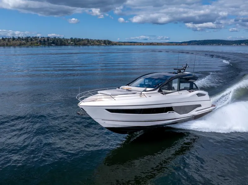 Slide: The Image of 2025 Sunseeker Predator 55 yacht cruising on a serene lake under a partly cloudy sky. - 9