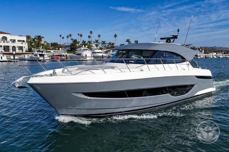 The Image of 2026 Riviera 4600 Sport Yacht Platinum Edition cruising in a sunny marina. - 0