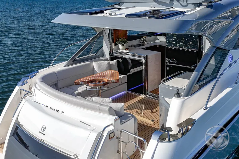 Slide: The Image of 2026 Riviera 4600 Sport Yacht Platinum Edition on water, featuring luxurious deck and seating area. - 20