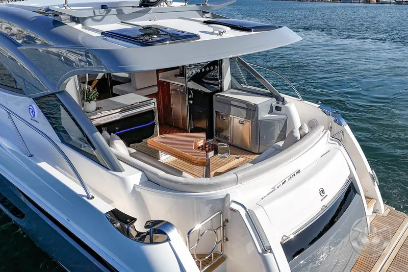 Slide: The Image of 2026 Riviera 4600 Sport Yacht Platinum Edition on water, featuring luxurious outdoor seating and amenities. - 21