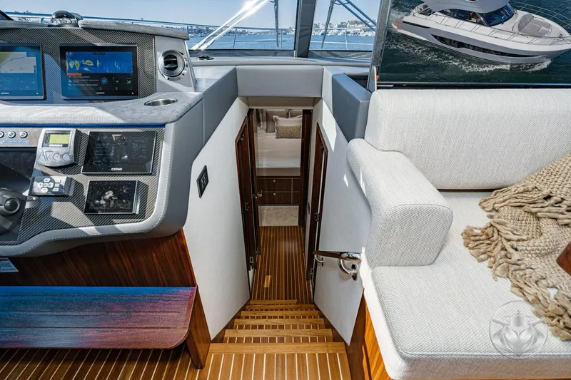 Slide: The Image of Interior of 2026 Riviera 4600 Sport Yacht Platinum Edition, featuring helm and cabin entrance. - 41