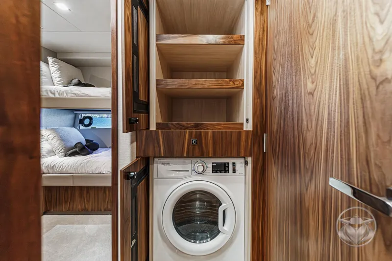 Slide: The Image of 2026 Riviera 4600 Sport Yacht interior with laundry area and cozy bunk beds. - 54