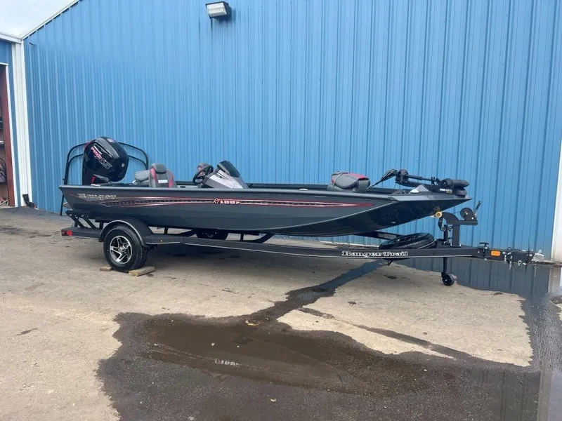 The Image of 2023 Ranger RT188P fishing boat on trailer, parked by blue building. - 0