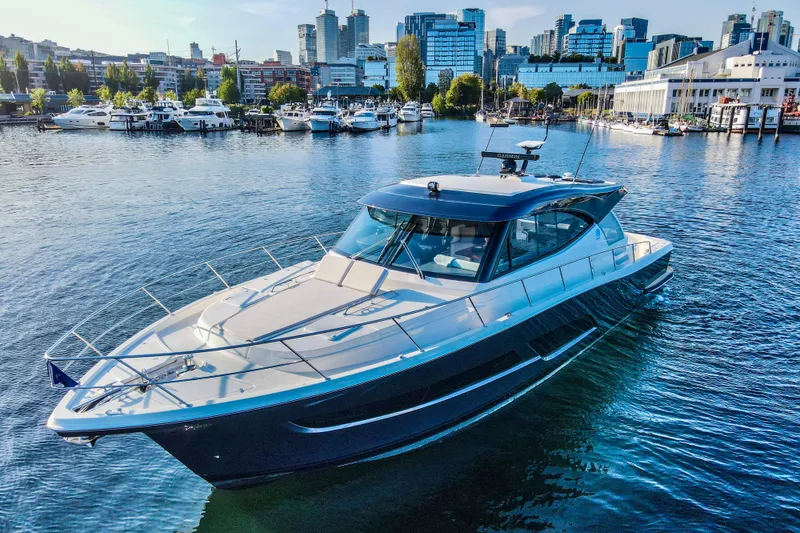 The Image of 2026 Riviera 505 SUV yacht cruising on a calm lake with cityscape background. - 0