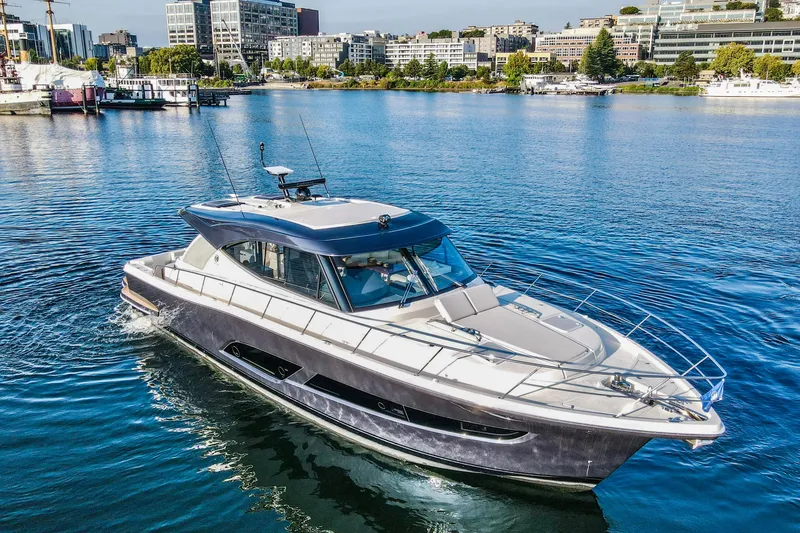 Slide: The Image of 2026 Riviera 505 SUV yacht cruising on a serene lake with industrial backdrop. - 2