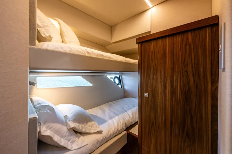 Slide: The Image of Luxurious 2026 Riviera 505 SUV yacht cabin with cozy bunk beds and elegant wood finish. - 46