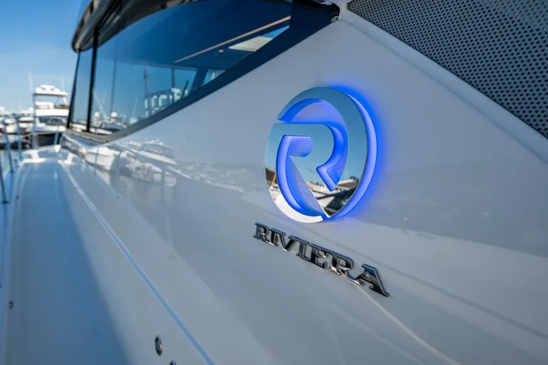 Slide: The Image of 2026 Riviera 505 SUV yacht with illuminated logo, docked at marina. - 63