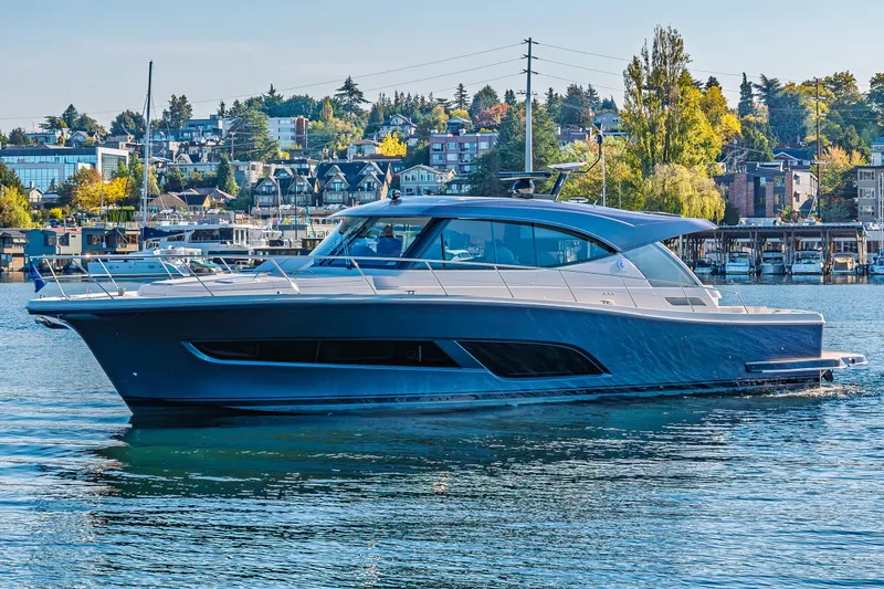 Slide: The Image of 2026 Riviera 505 SUV yacht cruising on a scenic waterfront with houses and trees. - 65
